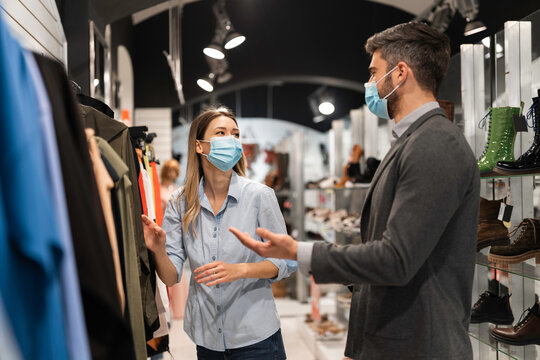 People shopping clothes at a store while wearing masks