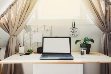 modern workplace. wooden desk with laptop mockup white empty screen, mood board with pined notes, green plants at work space in home office room interior in neutral tones. Selective focus, Copy space