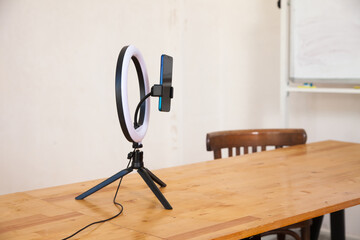  Ring lamp on  tripod with  mobile phone   on  table in  room