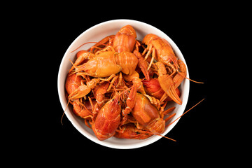 Round dish with red boiled crayfish isolated on black