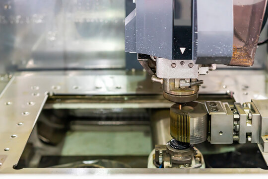 Close up nozzle and wire guide control feed unit of high technology and precision cnc edm electric wire cut machine with product during process forming in manufacturing process at factory