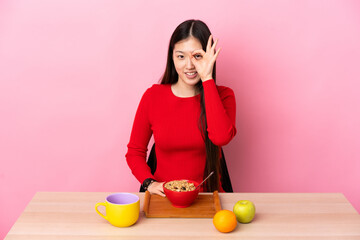 Young Chinese girl  having breakfast in a table showing ok sign with fingers