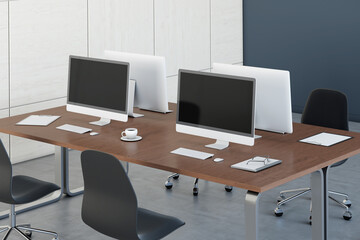 Blank black computer monitors on dark wooden tables in open space office with black and white walls. 3D rendering, mock up