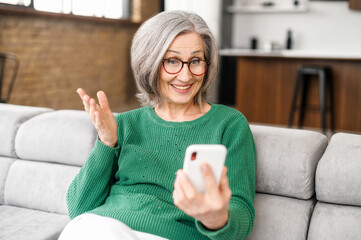 Video call concept. Smiling mature woman talking online via video connect on the smartphone, senior female stay in touch with family or friends during pandemic period