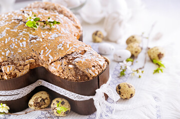 Traditional Italian desserts for Easter - Easter dove. Festive pastries with almonds and sugar icing on a light background and flowering branches, Easter decor and eggs. close-up