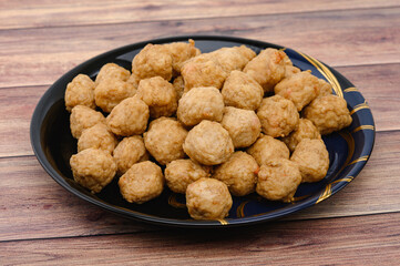Meat or Fried Shrimp Balls placed in a black plate  and place on wooden table.