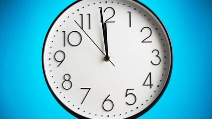Analog white wall clock on blue background. Clock in closeup.
