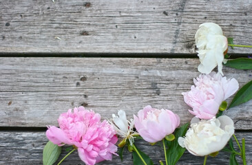 Beautiful pink and white pion flowers on wooden table. Flowers frame. Mock up for text. Copy space.