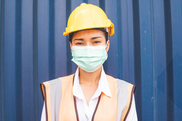 Fototapeta na wymiar Portrait of Asian logistic engineer worker woman wear protective mask looking at camera. working during Coronavirus epidemic at container warehouse construction site. 