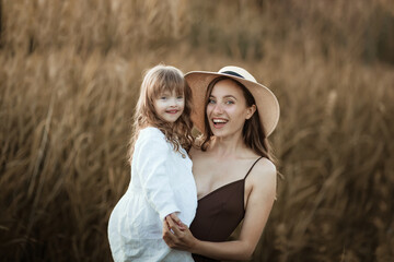 Charming Caucasian young mom holds her daughter with Down syndrome, beautiful special motherhood,...