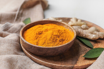 Bowl with turmeric powder on plate, closeup