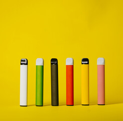 Set of colorful disposable electronic cigarettes with shadows on a yellow background. The concept of modern smoking, vaping and nicotine