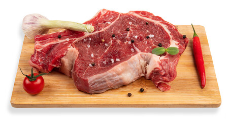 Raw meat on a chopping board. Pepper, garlic, cherry tomato.
