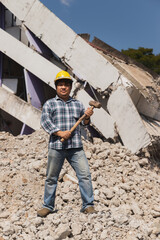 Construction worker holding a sledge hammer standing on demolish building and looking at the camera. Earthquake. industry.