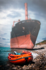The red-and-black ship ran aground. In the foreground, an inflatable boat moored to the shore....
