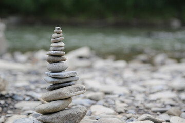 Fototapeta na wymiar Pyramid of stones on the banks of a mountain river