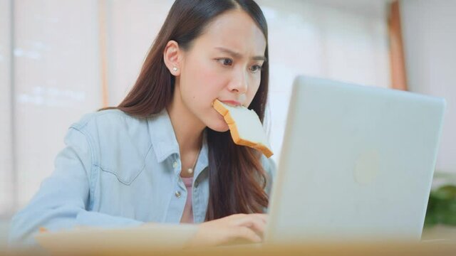 Asian beautiful girl feeling hungry while working on computer at home.