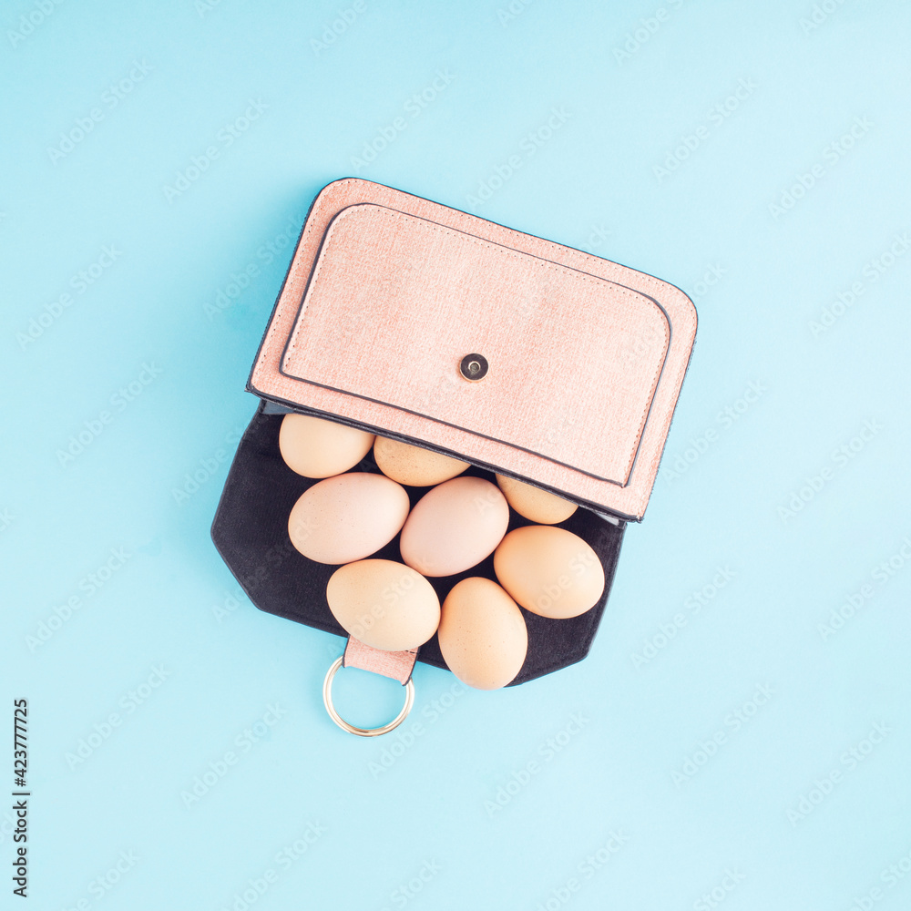 Wall mural Eggs in a small female purse. Minimal Easter concept on blue background