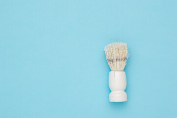 Fototapeta na wymiar Stylish white shaving brush on a light blue background.