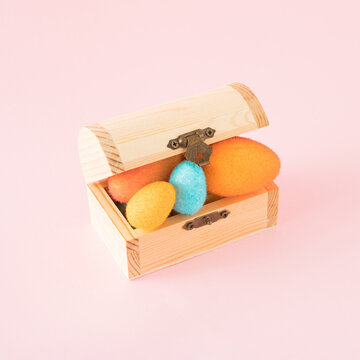 Colorful Eggs in a wooden cofin . Minimal Easter concept on bright pink background