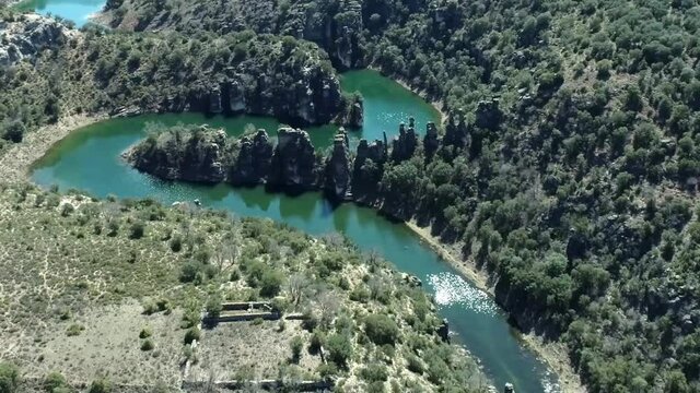 Meandros de aguas de color turquesa hasta el embalse, presididos por la alineaci&oacute;n de los monolitos naturales de Los Frailes