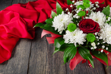 Bouquet of scarlet roses and chrysanthemums on wooden background and fabric