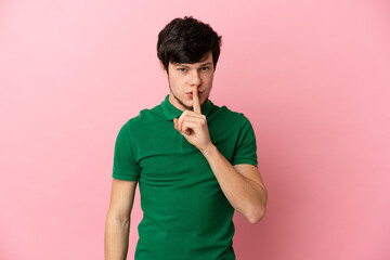 Young Russian man isolated on pink background showing a sign of silence gesture putting finger in mouth