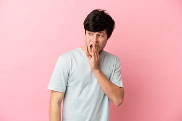 Fototapeta na wymiar Young Russian man isolated on pink background whispering something with surprise gesture while looking to the side
