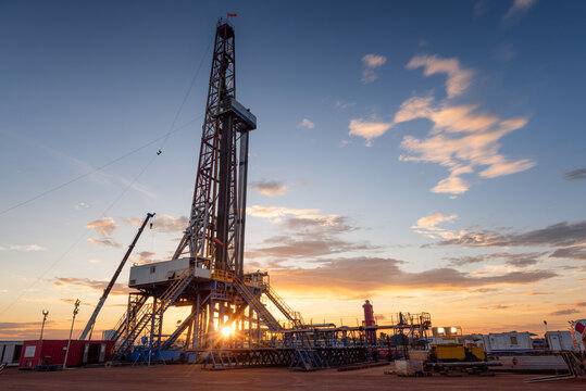 Sunrise at drilling rig in oil field, onshore petroleum industry