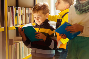 Child in school library. Kids read books. Little boy with his friends reading and studying. Three children at bookstore. Smart intelligent preschool kid choosing books.