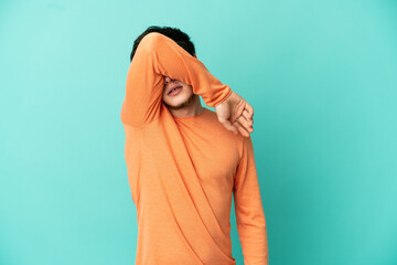 Young Russian man isolated on blue background covering eyes by hands