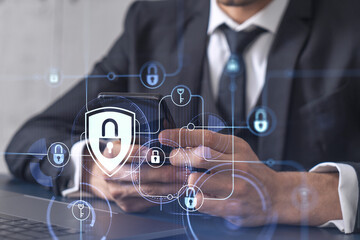 A programmer is browsing the Internet in smart phone to protect a cyber security from hacker attacks and save clients confidential data. Padlock Hologram icons over the typing hands. Formal wear.