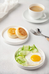 Eggs, cucumber in a plate and curd pancakes on the table.  Healthy breakfast