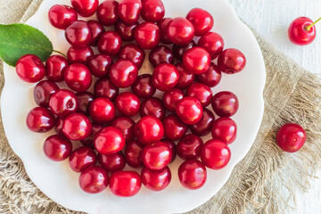 Sweet cherry in a plate close up on a white background. Top view.
