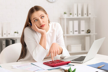 Bored female accountant with calculator working in office