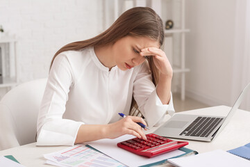 Stressed female accountant with calculator working in office