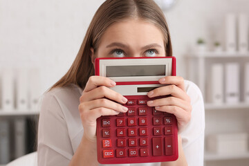 Stressed female accountant with calculator working in office