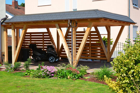Neuer Carport aus lasiertem Holz mit Kupfer-Dachrinne und Regenfallrohr und automatisches Metall-Einfahrtstor, alpine Architektur