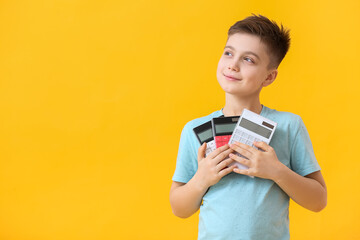 Little boy with calculators on color background