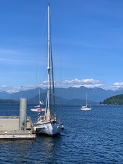 Amazing scene of a sailboat with Canada flag, docking at a marina, the beautiful sea, the distant mountains and islands make this place very special.