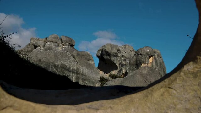 Pov forward through hole of limestone rock and rock formation set in background during blue sky. Castle Hill Conservation Area,New Zealand.