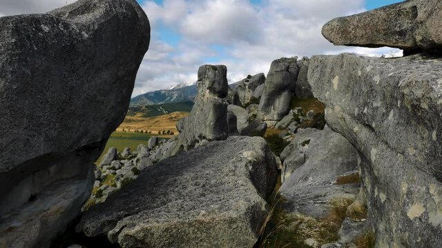 Close up shot of famous rock formation landmark at Castle Hill and beautiful rural landscape with mountains in backdrop. South Island,New Zealand.