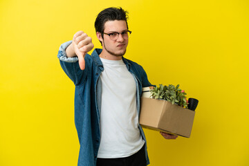 Russian Man making a move while picking up a box full of things isolated on yellow background...