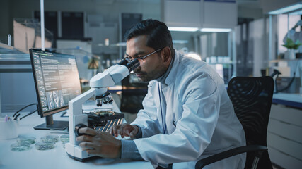 Medical Research Scientist Conducts DNA Experiments Under a Microscope and Writes Results on...