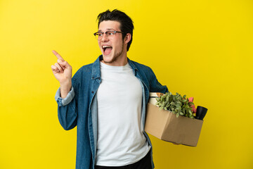 Russian Man making a move while picking up a box full of things isolated on yellow background...