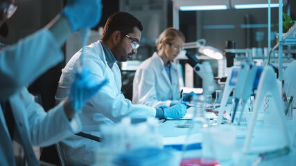 Team of Medical Research Scientists Conduct Experiments with Help of Microscope, Test Tubes, Micropipettes, Using Tablet Computer. Modern Biological Applied Science Laboratory with Diverse Colleagues.