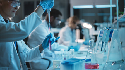Female Research Scientist Uses Micropipette to Mix Liquids in a Sample Test Tube in a Modern...