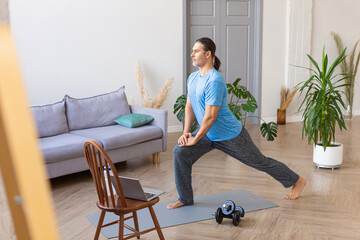 Photo of a middle aged man during online home workout- he using a tutorial from the Internet....