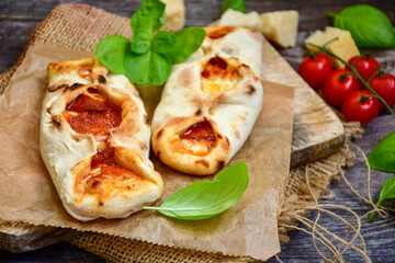 Home made italian  mini calzone  salami pizza with  tomatoes, mozzarella and parmesan cheese and fresh basil 