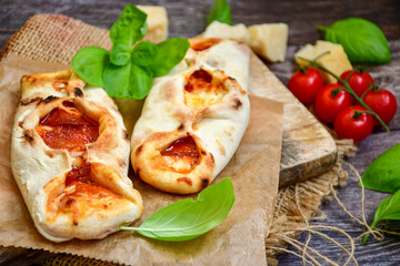 Home made italian  mini calzone  salami pizza with  tomatoes, mozzarella and parmesan cheese and fresh basil 
